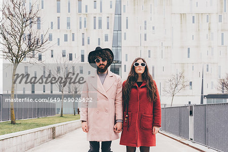 Portrait of young couple in urban setting, wearing sunglasses, holding hands