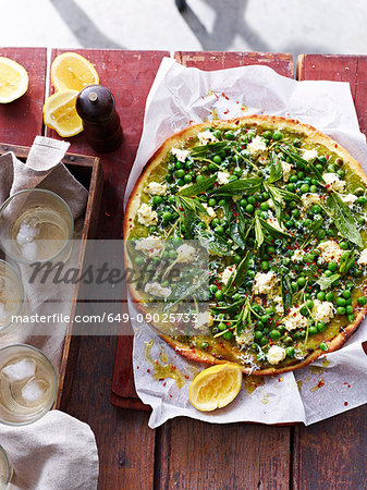 Spring peas, mint and salted ricotta pizza on serving board, elevated view