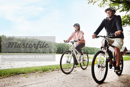 Mature couple cycling beside lake