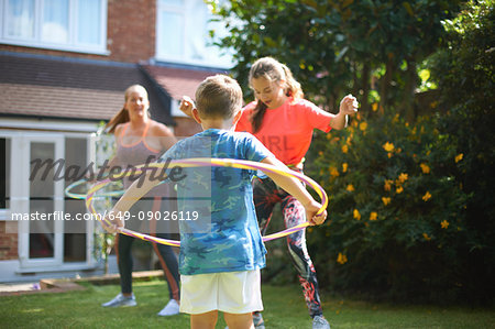 Mature woman with son and teenage daughter hula hooping in garden