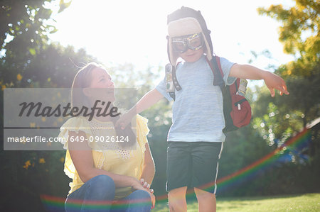 Mature woman with son pretending to be pilot with arms open in sunlit garden