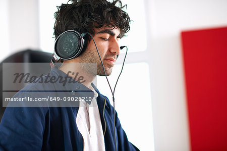 Young male college DJ student listening to music on headphones