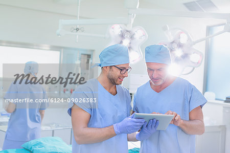 Male surgeons talking, using digital tablet in operating room