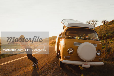 Young male skateboarder skateboarding on rural road at sunset, Exeter, California, USA