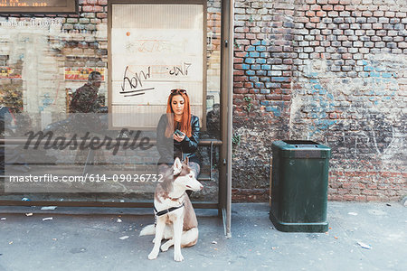 Red haired woman with dog waiting at bus stop