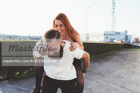 Man giving red haired woman piggyback