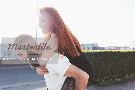 Man giving red haired woman piggyback