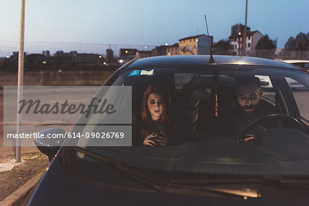 Couple in car at night using smartphone