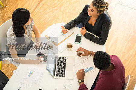 Overhead view of three businesswomen and men meeting at office table