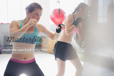 Determined female boxers shadowboxing in gym