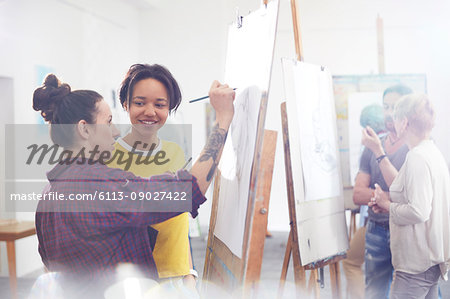 Female artists sketching at easel in art class studio