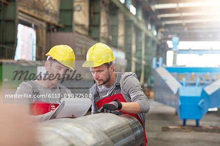 Male workers with clipboard in factory