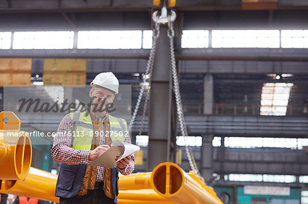 Portrait confident male foreman writing on clipboard in factory