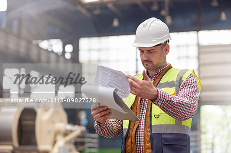 Male foreman reviewing paperwork on clipboard in factory