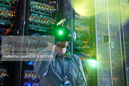 Male computer programmer using virtual reality simulator glasses and glowing glove in server room