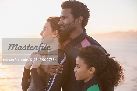 Serene affectionate family looking away on summer sunset beach