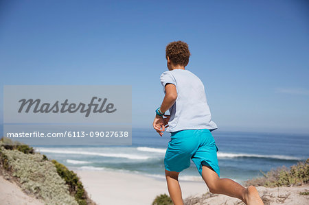 Pre-adolescent boy running on sunny summer ocean beach