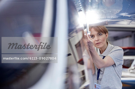 Focused female engineer mechanic examining airplane