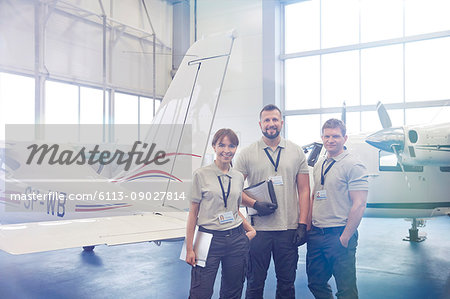 Portrait confident mechanic engineers standing in airplane hangar