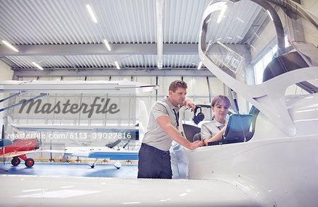 Mechanic engineers working in airplane cockpit in hangar