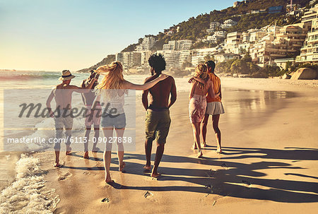 Young couple friends walking on sunny summer beach