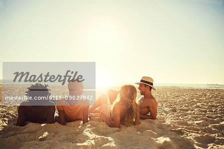 Young couples laying, relaxing on sunny summer beach