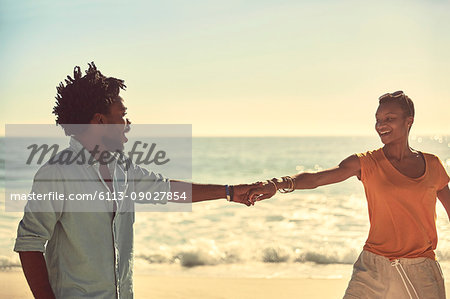 Affectionate young couple holding hands on sunny summer beach