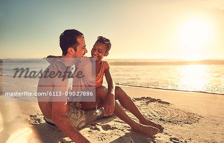 Affectionate young couple hugging on sunny summer ocean beach