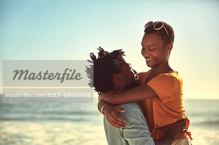 Affectionate young couple hugging on sunny summer beach