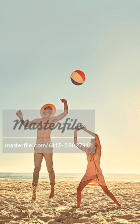 Young couple playing with beach ball on sunny summer beach
