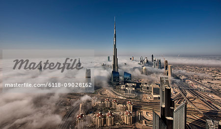 Aerial view of Dubai, United Arab Emirates, with Burj Khalifa and other skyscrapers above the clouds.