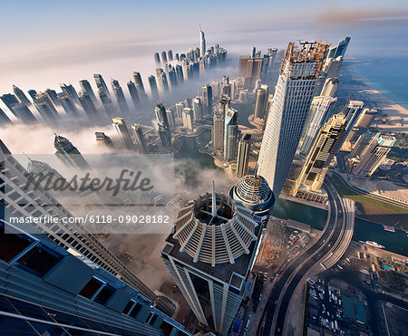 Aerial view of cityscape with skyscrapers above the clouds in Dubai, United Arab Emirates.
