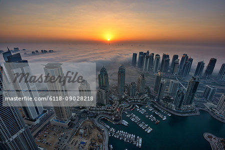 Aerial view of the cityscape of Dubai, United Arab Emirates at dusk, with skyscrapers and the marina in the foreground.