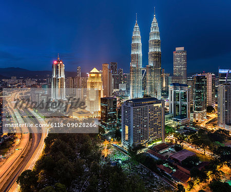 Cityscape of Kuala Lumpur, Malaysia at dusk, with illuminated Petronas Towers.