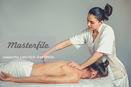 Massage gua, sha therapy. A young professional female masseur makes Thai massage. Patient is lying down on a bed and is covered with white towel. Treatment, rest, relaxation, health care, medicine