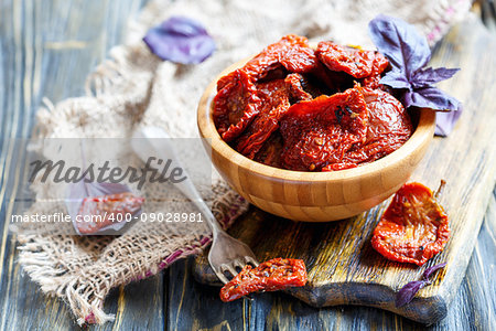 Bowl with sun-dried tomatoes and fork on wooden table,selective focus.