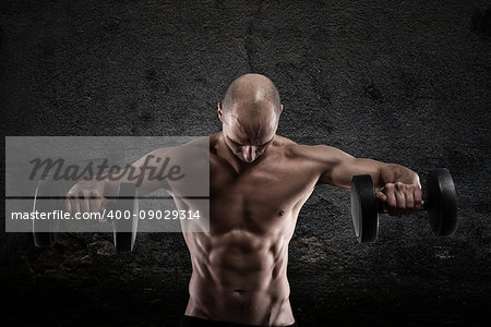 Athletic muscular man training biceps with dumbbells