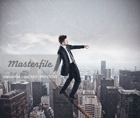 Businessman is balancing on a rope over a city