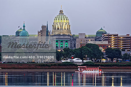 Harrisburg Pennsylvania skyline with State Capital Building and a river boat in the foreground. Tents are set up in the park for Memorial Day festivities. The view is from across the Susquehanna River.