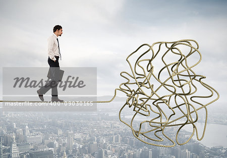 Problem and difficulty concept with a businessman who walk on a tangled rope