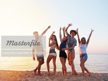 Happy group of friends raising their hands to the sky