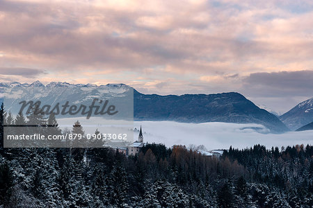 Italy, Trentino Alto Adige, Non valley, Dawn on Maddale group and fog over the Seio village in a winter day.