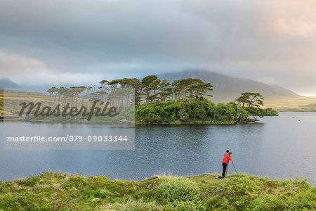 Photographer in front of Pine Island on Derryclare Lake. Connemara, Co. Galway, Connacht province, Ireland.