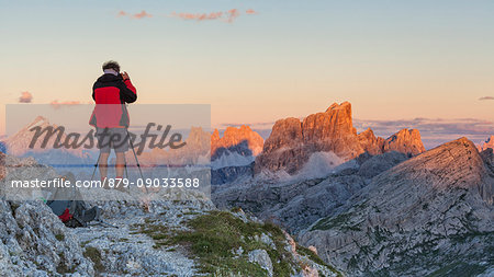 Europe, Italy, Veneto, Belluno, Cortina d Ampezzo. Landscape photographer at sunset on the top of Sass de Stria, Dolomites