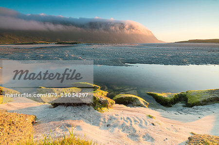 The midnight sun is reflected in the cold sea at summer Fredvang Moskenesøya Nordland county Lofoten Islands Norway Europe