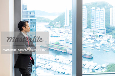 Businessman looking out of window at view of harbour