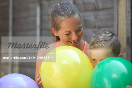 Mother and son in garden, holding balloons