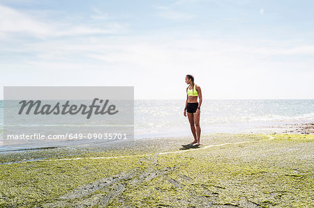 Young woman standing beside sea, looking at view