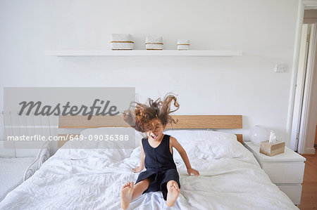 Young girl jumping on bed