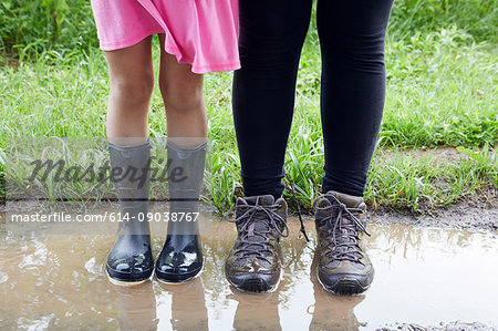 Two girls standing in mud, low section